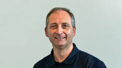 Matthias trägt ein dunkelblaues Poloshirt und lächelt in die Kamera.