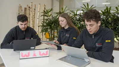 Auszubildende sitzen an einem Tisch vor Tablets.