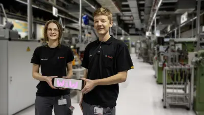 Zwei Auszubildenende hatlen ein Schild mit dem Schriftzug „WiW“