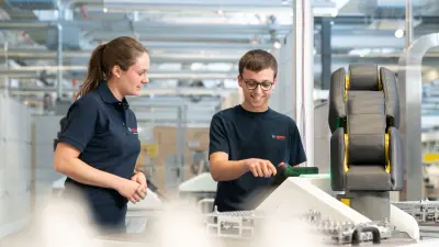 Ein Azubi erklärt in der Ausbildungswerkstatt einem anderen Azubi die Steuerung einer Maschine