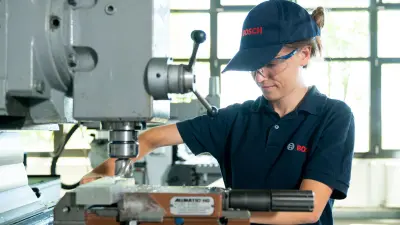 Ein weiblicher Azubi arbeitet an der Bohrmaschine