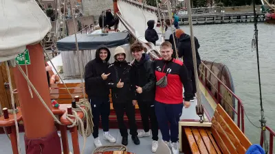 Vier Azubis auf einem Segelschiff lachen in die Kamera