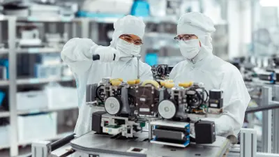 Mitarbeiter im Reinraum montiert eine hochpräzise Maschine in einer Halbleiterfertigung und arbeitet konzentriert an der Anlage.