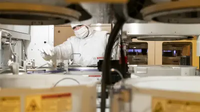 Mikrotechnologe in Reinraumbekleidung bei der Bedienung einer Fertigungsanlage im Bosch Halbleiterwerk Dresden