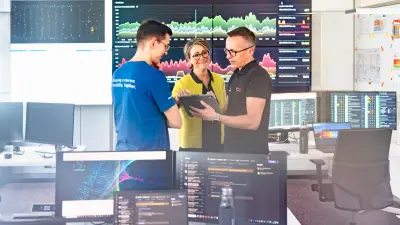 Drei Personen im Kontrollraum von Bosch in Dresden betrachten ein Tablet vor Monitoren mit Echtzeitdaten