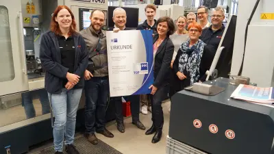 Team der Robert Bosch GmbH in Hildesheim erhält IHK-Auszeichnung für Top-Ausbildung – engagierte Mitarbeitende vor moderner Ausbildungsmaschine