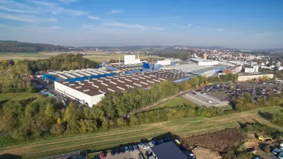 Luftaufnahme des Bosch-Werks in Lollar mit Parkplätzen, Hallen und umliegender Landschaft im Sonnenschein.
