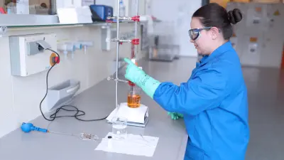 Eine Auszubildende der Mikrotechnologie bei Bosch führt eine chemische Titration mithilfe eines Farbindikators im Labor durch.