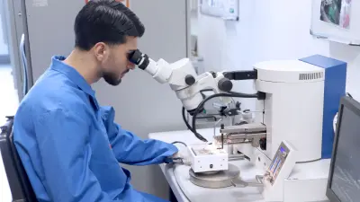 Ein Auzubildender der Mikrotechnologie bei Bosch überprüft im Labor anhand eines Mikroskops Verbindungsstellen eines Loops.