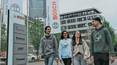 Vier junge Menschen laufen lachend vor dem Bosch-Gebäude mit Logo-Flaggen und Marken-Schildern.