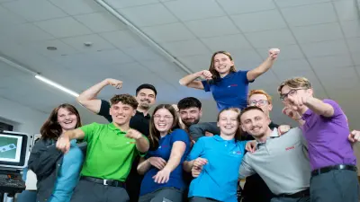 Eine Gruppe lachender Jugendlicher in bunten Shirts ballt die Fäuste 