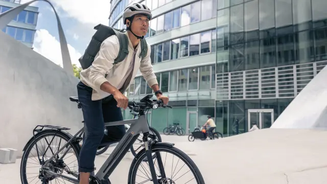 Junger Mann fährt auf eBike vor modernem Gebäude