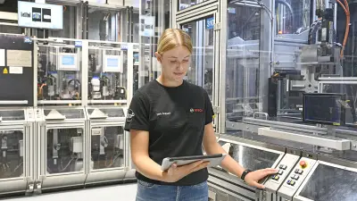 Eine Frau arbeitet mit Tablet in einer automatisierten Fertigungslinie