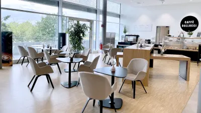 Die Cafeteria bei Bosch in Dresden: mehrere kleine schwarze Tische mit bequemen braunen Sesseln, im Hintergrund die Kuchentheke.