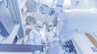Zwei Ingenieure stehen im Reinraum an einer Anlage, um sich zu beraten. 