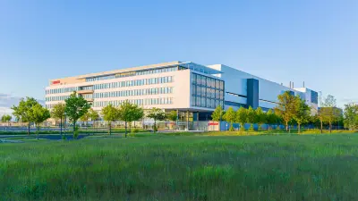 Blick auf den Bosch Standort in Dresden: im Vordergrund eine grüne Wiese, dahinter die Waferfab.