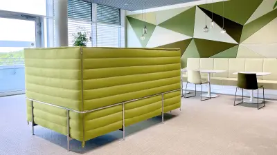 Eine der vielen Lounges bei Bosch in Dresden: ein offener Raum mit einer großen grünen Couch sowie weiteren Tischen und Stühlen. 