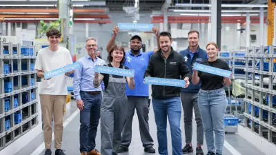 Gruppe von sieben Mitarbeitenden in einer Fertinungshalle