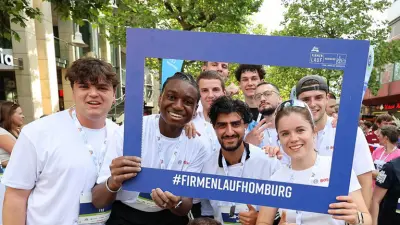Gruppe von Teilnehmenden posiert beim Firmenlauf hinter einem Bilderrahmen.