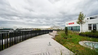 Begrünte Dachterasse mit Blick auf die Berge, an der Gebäudewand rechts das Logo der Firma Bosch