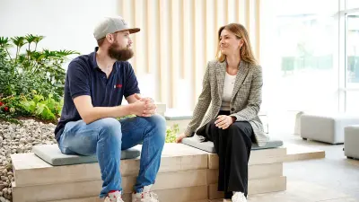 Zwei Mitarbeiter der Firma Bosch sitzen nebeneinander in einem Empfangsbereich und unterhalten sich