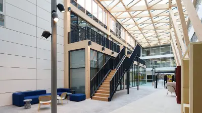 Lichtdurchfluteter Durchgangsbereich in einem Bürogebäude mit Treppen und Lounge-Möbeln