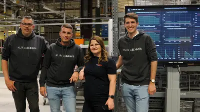 Team von vier Personen neben einem Monitor mit digitalen Daten der Produktionslinie 