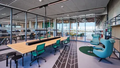 Ein heller Büroraum mit verglasten Wänden, zwei Sesseln und einem langen Arbeitstisch mit Bürostühlen bei Bosch eBike Systems in Kusterdingen.