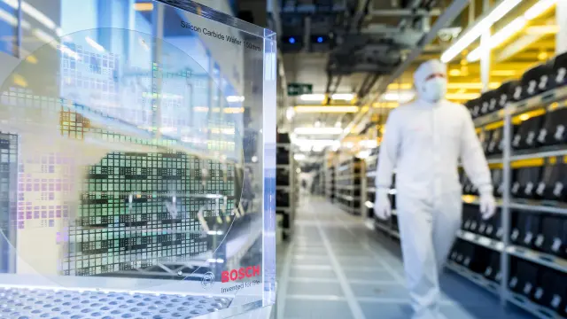 Ein Mann in einem weißen Reinraum-Overall läuft durch ein Labor.