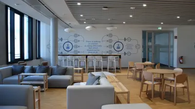 Lounge Bumblebee im Service & Supply Chain Campus mit gemütlicher, blauer Sofa-Ecke und langem Stehtisch vor Zitatwand There is nothing so useless as doing efficiently that which should not be done at all.