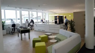 Lounge im IT-Campus aus dem Jahr der Eröffnung des IT-Campus 2017 mit Blick auf den Tischkicker Kaffeemaschinen Menschen in Erholungs- und Gesprächssituationen.