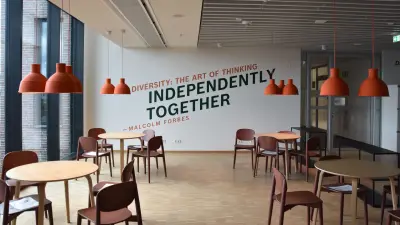 Lounge in den Farben orange und braun im Service & Supply Chain Campus mit Diversity Zitat von Malcom Forbes an der Wand Independently together.