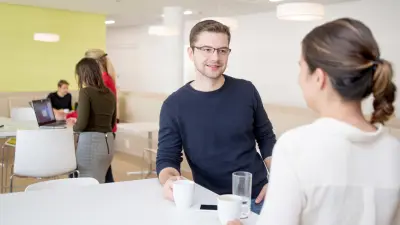 Lounge im IT-Campus mit Mitarbeitenden in Gesprächs- und Arbeitssituationen aus dem Jahr der Eröffnung des IT-Campus 2017.