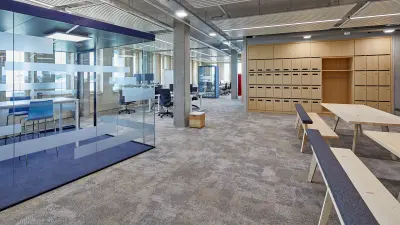 Modernes Büro mit offenem Grundriss, verschiedenen Arbeitsplätzen, darunter Schreibtische, Gemeinschaftstische und Telefonzellen.