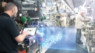 Mann arbeitet in der Fertigung mit einem Tablet in der Hand.