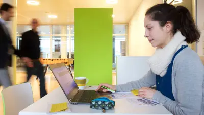 Frau sitzt in einem Büro vor dem Laptop.
