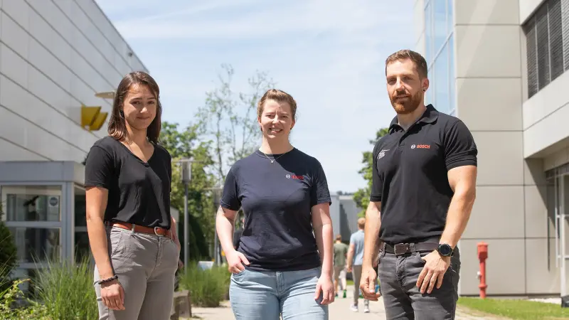 Chiara (links), Verena (Mitte) und Kevin (rechts) unterhalten sich vor dem Bosch-Gebäude und laufen auf die Kamera zu.