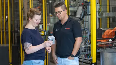 Verena prüft gemeinsam mit einem Kollegen lächelnd die Qualität eines Produkts.