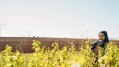 Gizem Dülger macht Fotos mit ihrer Kamera auf einem Feld.