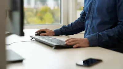 Zu sehen sind Christoph Dörrs Arme und ein Schreibtisch mit Computer-Bildschirm. Mit der einen Hand hält er die Computer-Maus, mit der anderen tippt er auf der Tastatur.