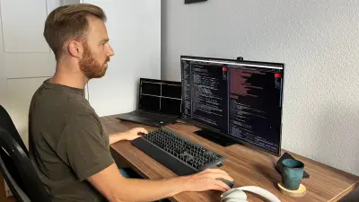 Christoph Dörr sitzt im Home Office an seinem PC und arbeitet – auf seinem Computer-Bildschirm erkennt man diverse Codes.