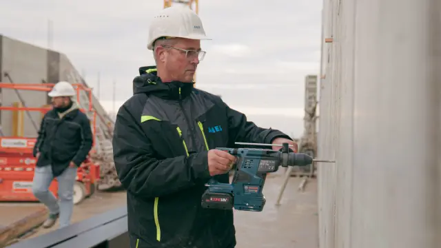 Frank Barthel, Mitarbeiter bei Anes Bau, bohrt in eine Wand.