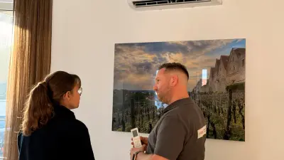 Mann mit Fernbedienung in der Hand erklärt einer Frau die Benutzung der Klimaanlage in einem Aufenthaltsraum.