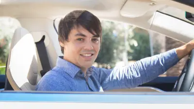 Moritz Dechant sitzt am Steuer eines Autos, im Profil, guckt in die Kamera. 