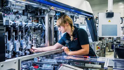Lara Wehrmeister bei der Arbeit an einer großen Maschine, im Profil. 