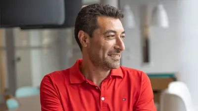 Mustafa verschränkt seine Arme und schaut lächelnd zur Seite. Er ist bis zum Oberkörper zu sehen.