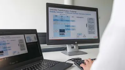 Simon sitzt am Computer und schaut sich eine Grafi k mit der Überschrift „S/4HANA Transformation Challenge“ an.