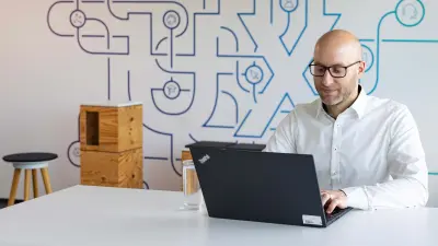 Simon arbeitet an seinem Laptop im UX-Studio und sieht zufrieden aus.