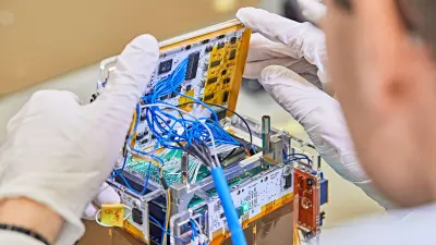 Ein Student hat den Mini-Satellit geöffnet, sodass man die innen liegende Technik sehen kann.
